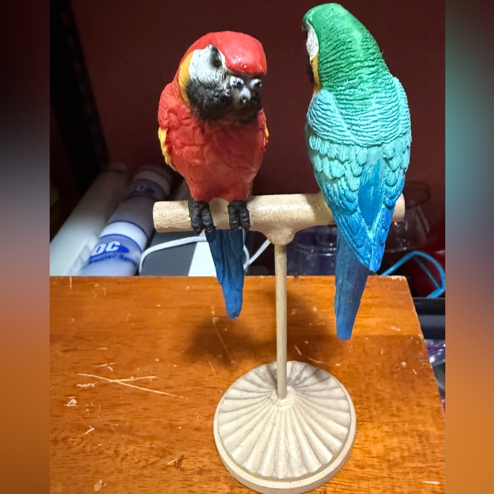 Two Stunning macaw figurines,a scarlet macaw and blue/yellow macaw,on a stand.